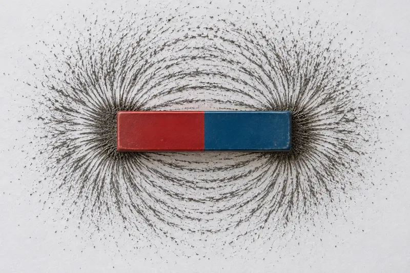 Iron filings forming curved patterns around the ends of a bar magnet.